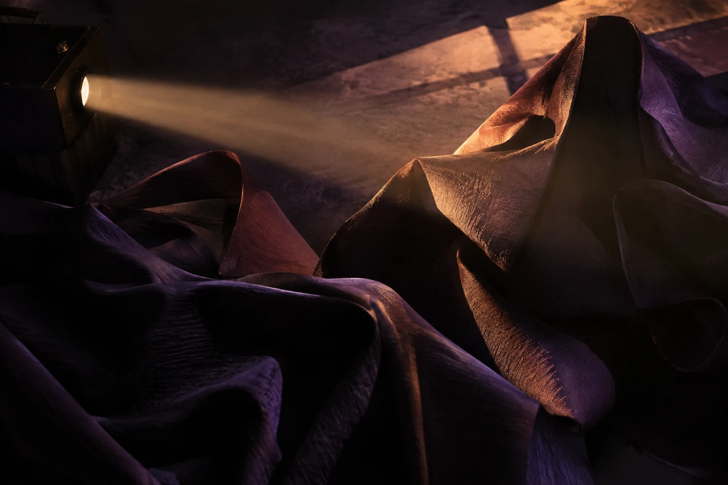 Projected light and shadow crossing sculptural fabric forms.