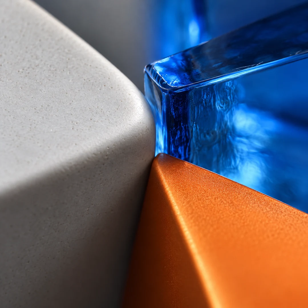Macro detail of pale gray ceramic, electric blue glass, and tangerine painted metal suggesting varied prepared-piano timbres